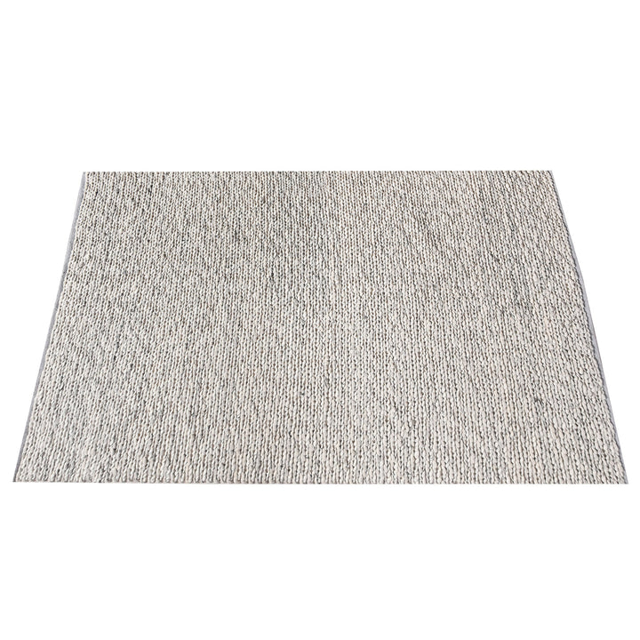 Rassi handwoven wool rug with a chunky braided weave in ivory, oatmeal and grey, in a living room