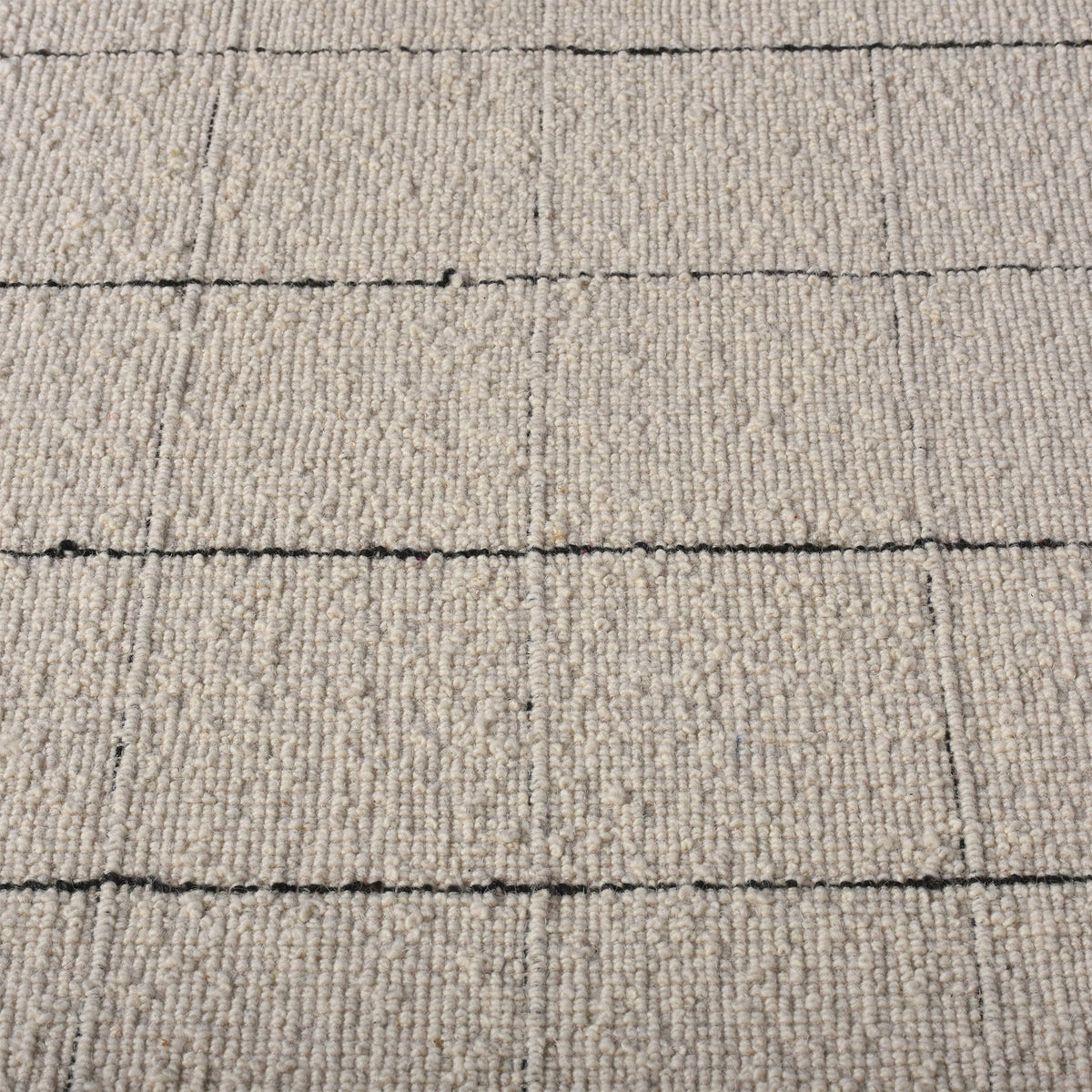 Khidki handwoven wool flatweave rug with fine charcoal grid lines on ivory, in a living room