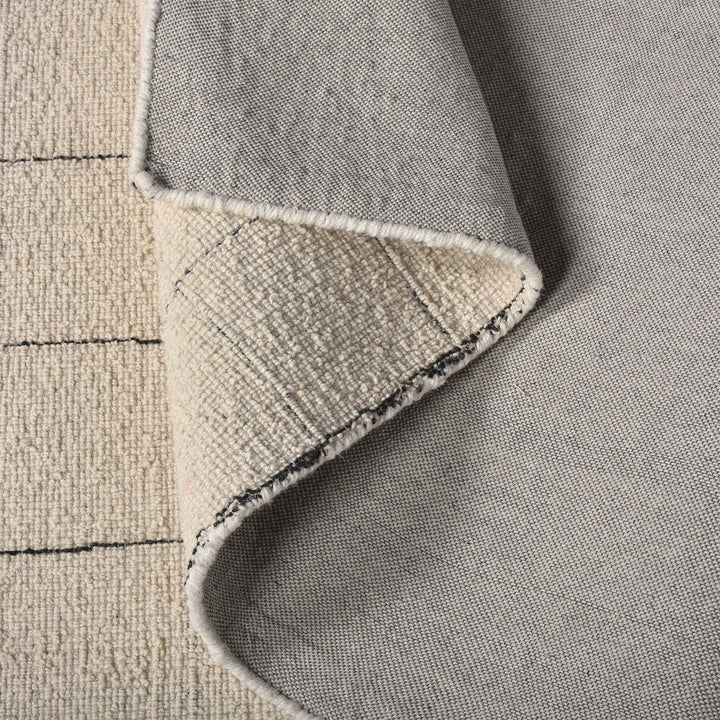 Khidki handwoven wool flatweave rug with fine charcoal grid lines on ivory, in a living room