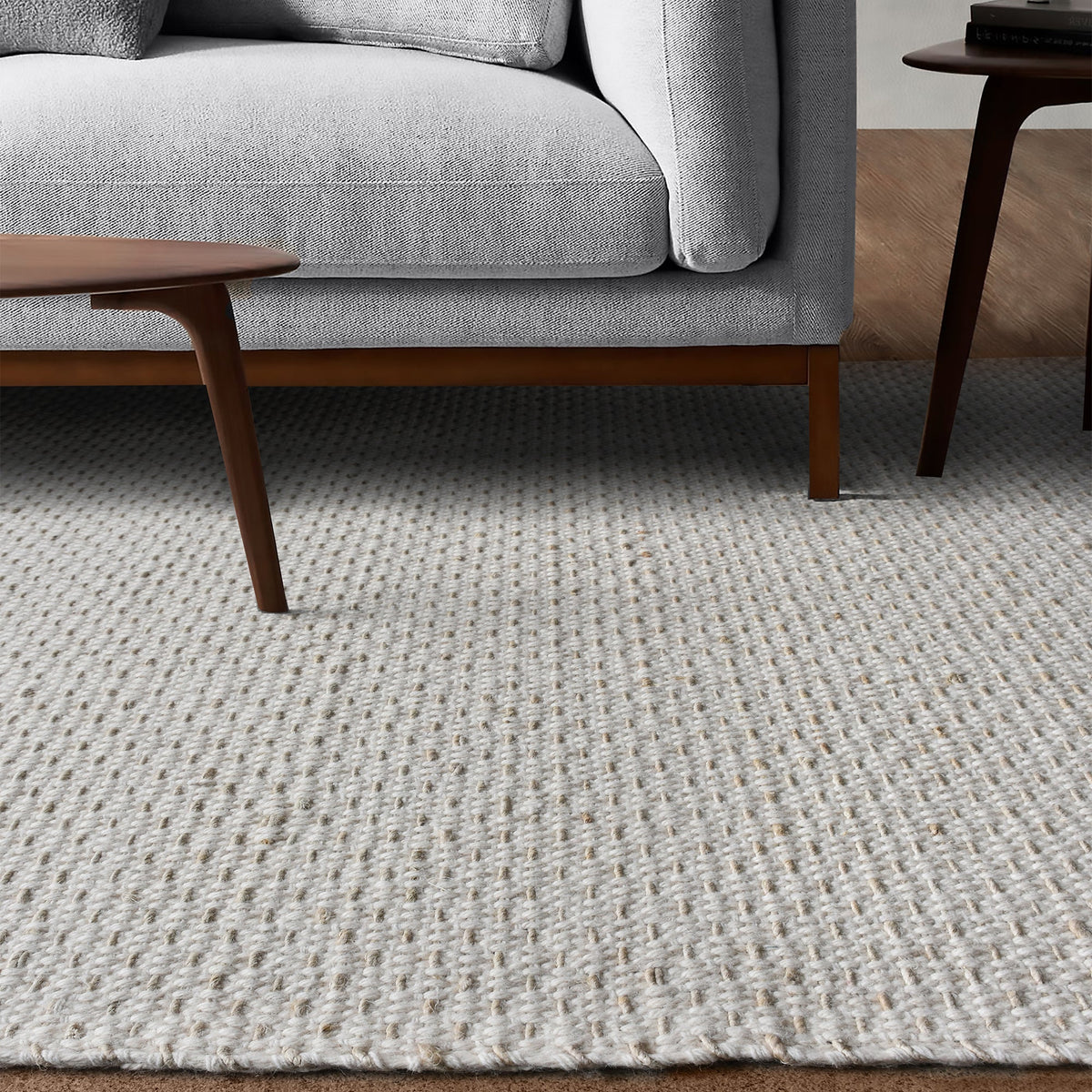 Kankar handwoven wool and jute rug in pale ivory-grey with a pebbled loop weave, in a bedroom