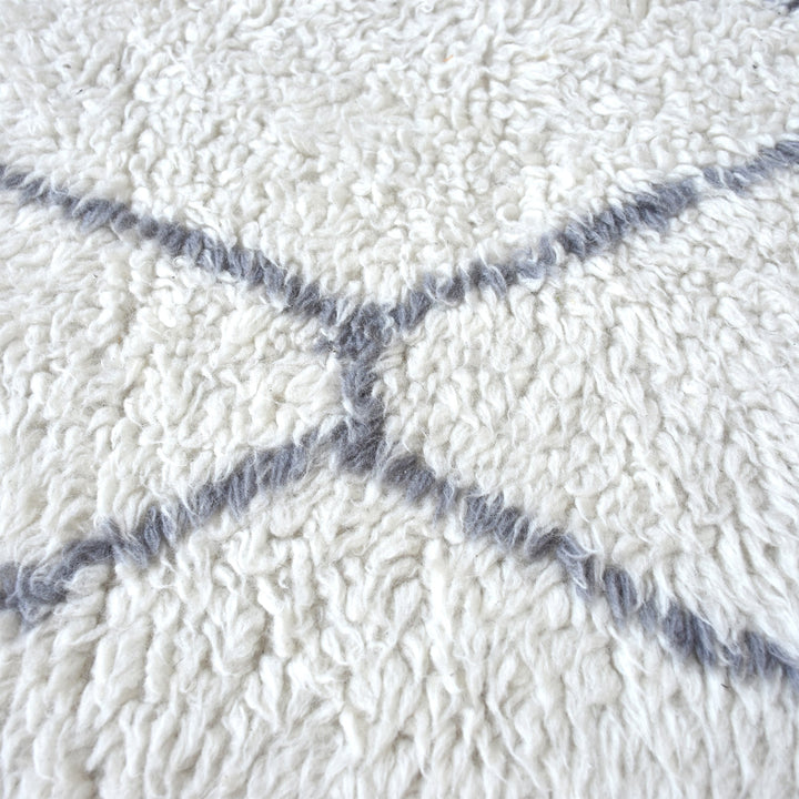 Kohra tufted New Zealand wool rug with a grey diamond lattice on white, in a living room