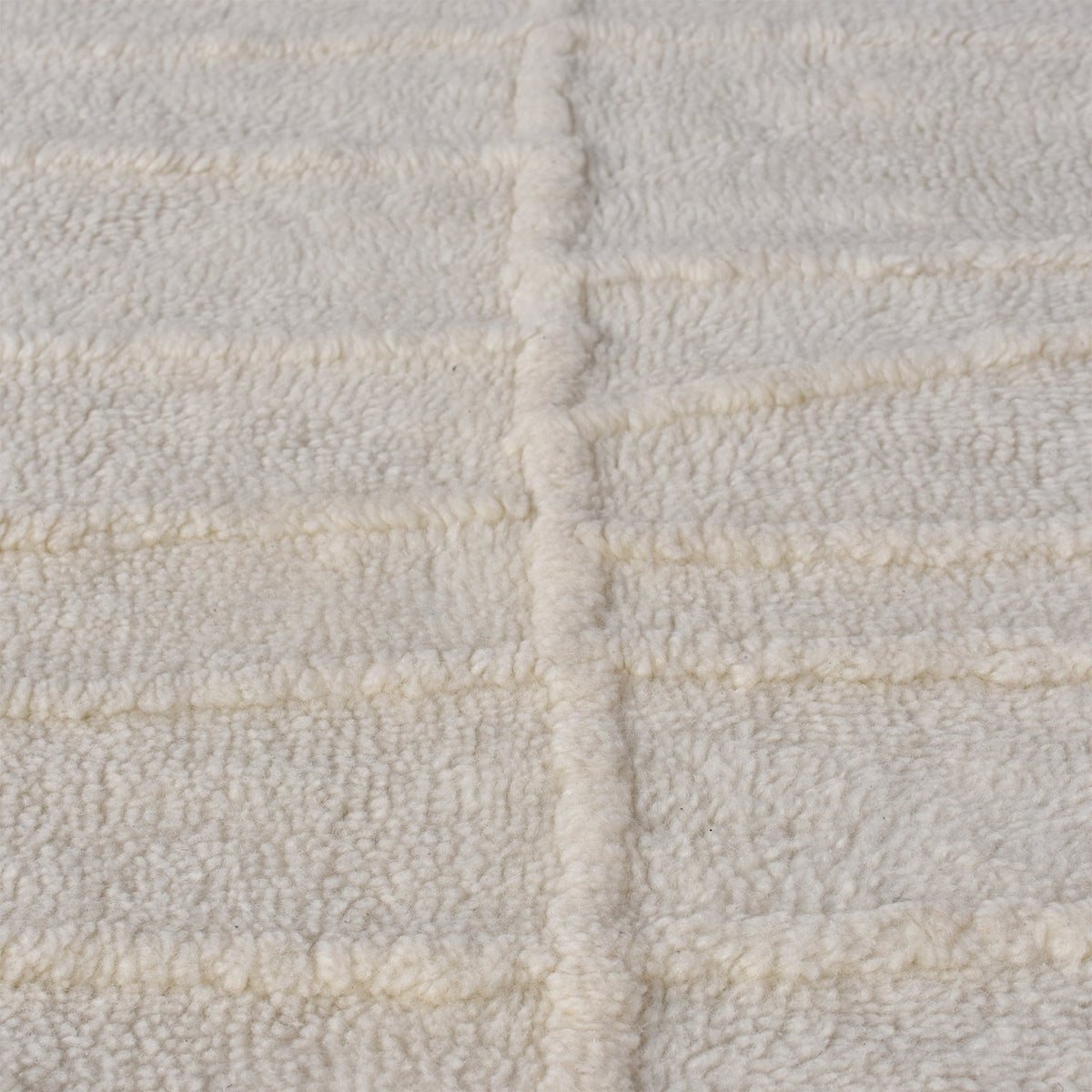 Swell tufted ivory New Zealand wool rug with carved waves and fringe, in a living room