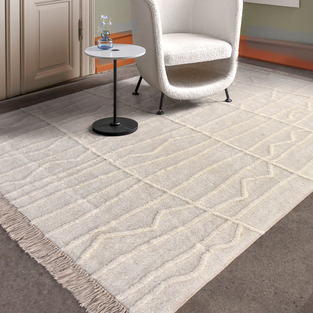 Swell tufted ivory New Zealand wool rug with carved waves and fringe, in a living room