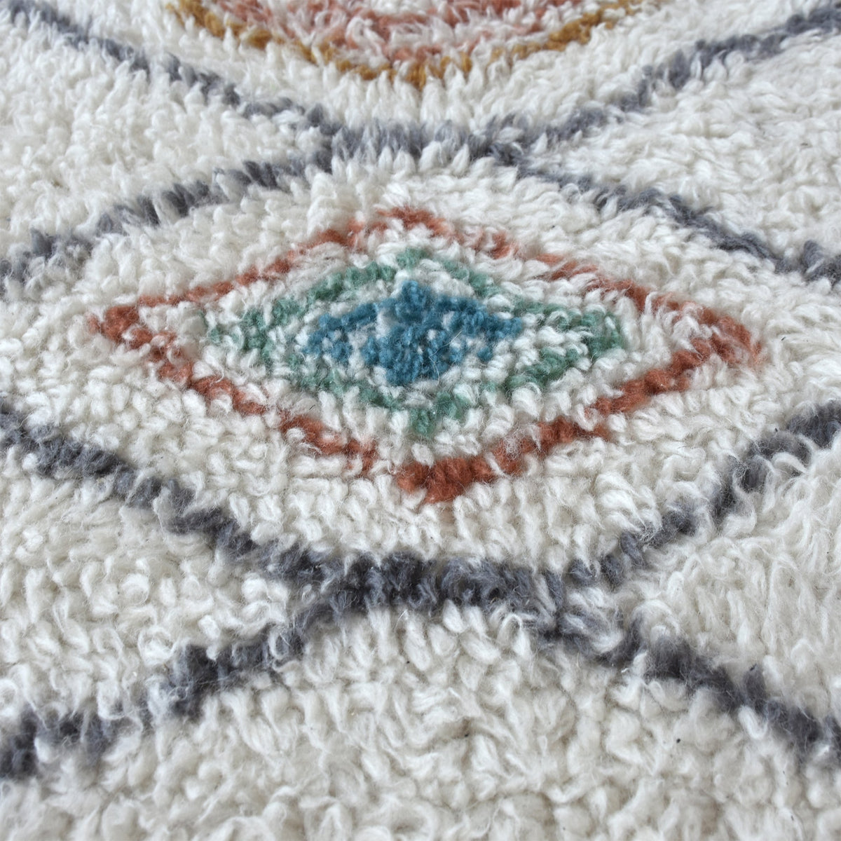 Mela tufted New Zealand wool rug with an ivory lattice and rust, teal and charcoal diamonds
