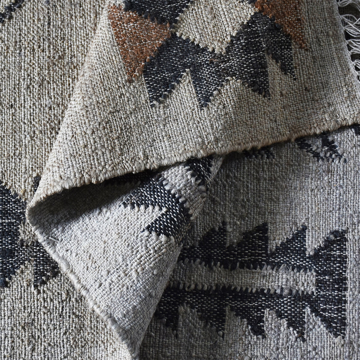 Terrain flatweave hemp rug with grey ground and terracotta and black motifs, in an entryway