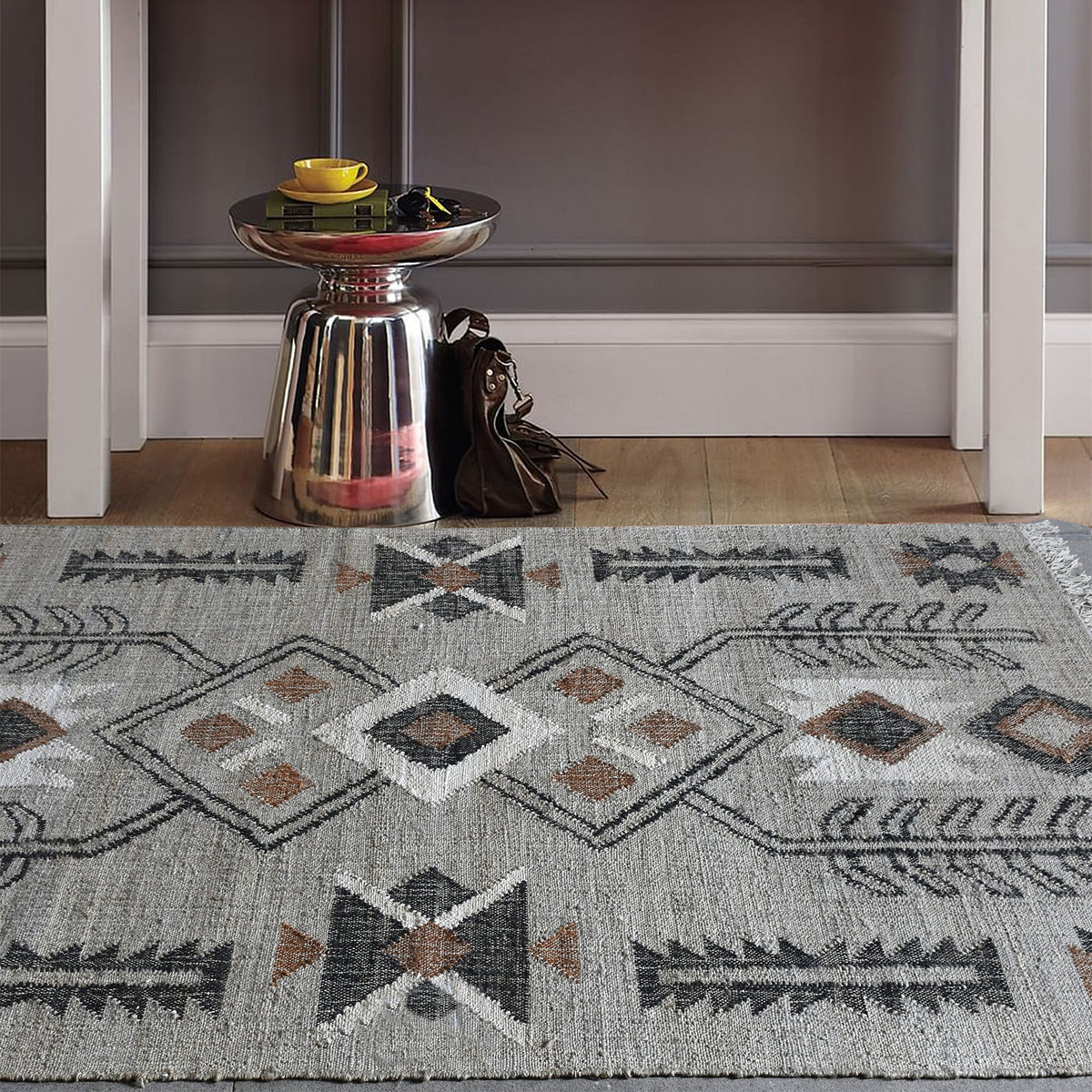 Terrain flatweave hemp rug with grey ground and terracotta and black motifs, in an entryway