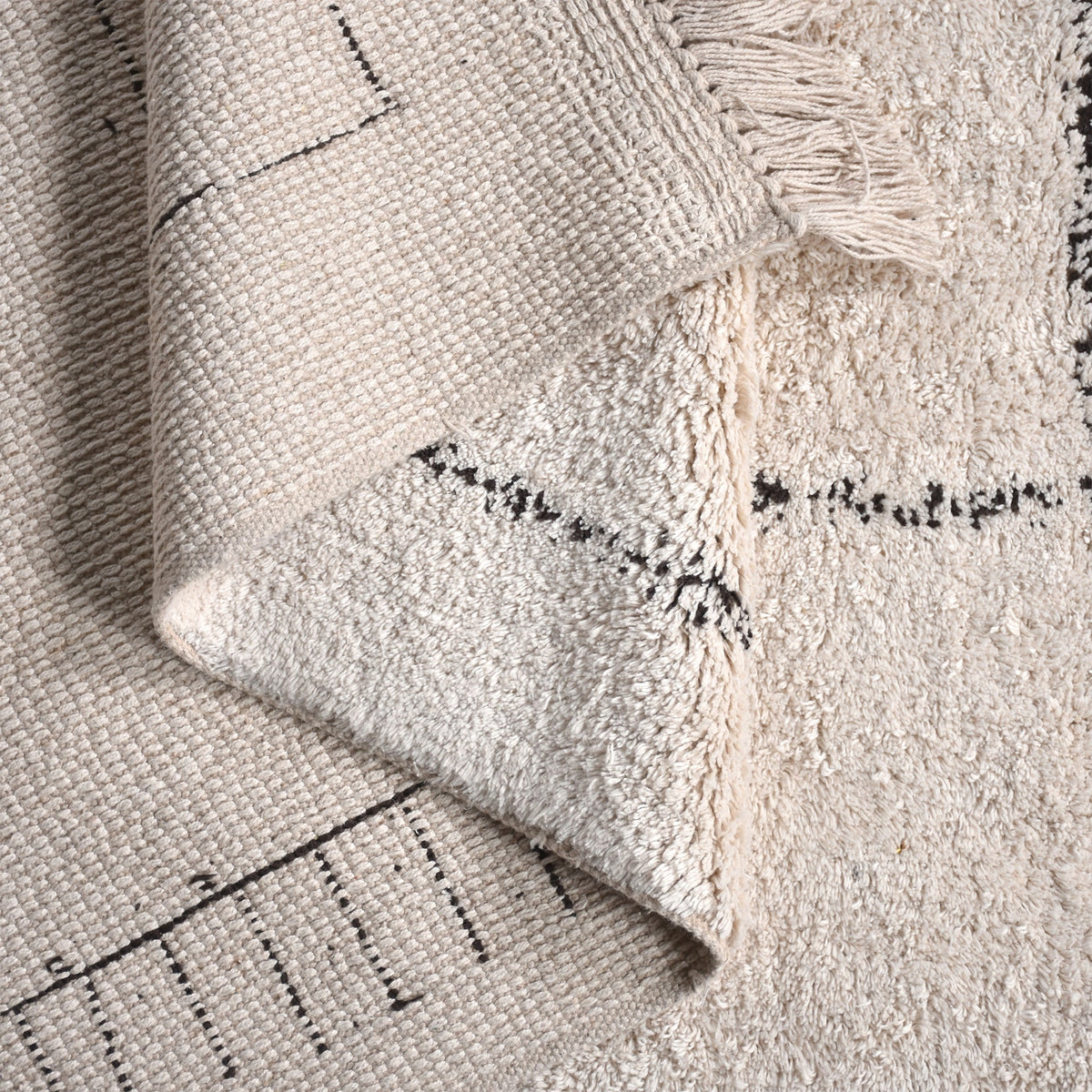Khaka tufted cotton rug with charcoal outline squares on ivory, in a living room