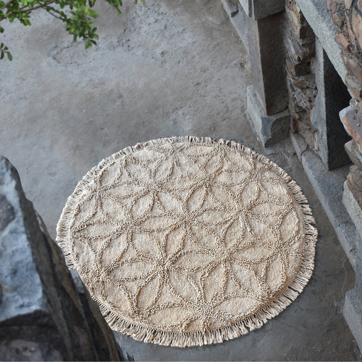 Phool round tufted cotton rug with a flower-of-life motif and fringe in raffia beige, in a bedroom