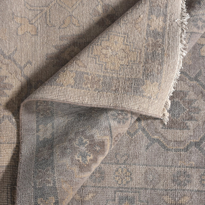 Yaad hand-knotted wool rug with distressed tribal medallions in pale taupe and rust, in a dining room
