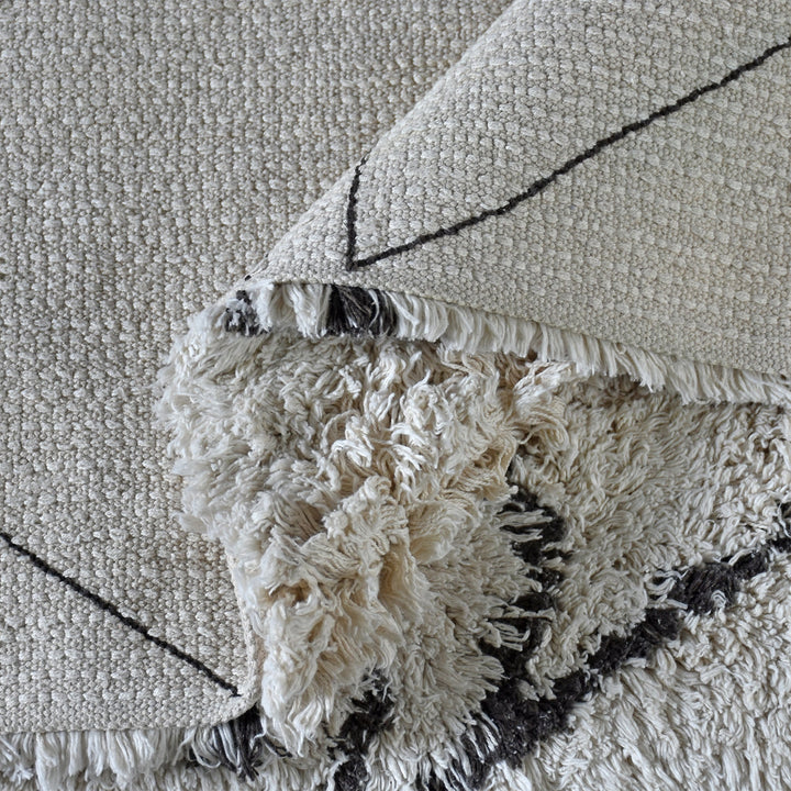 Lipi tufted cotton shag rug in ivory with a bold black lattice, in a bedroom