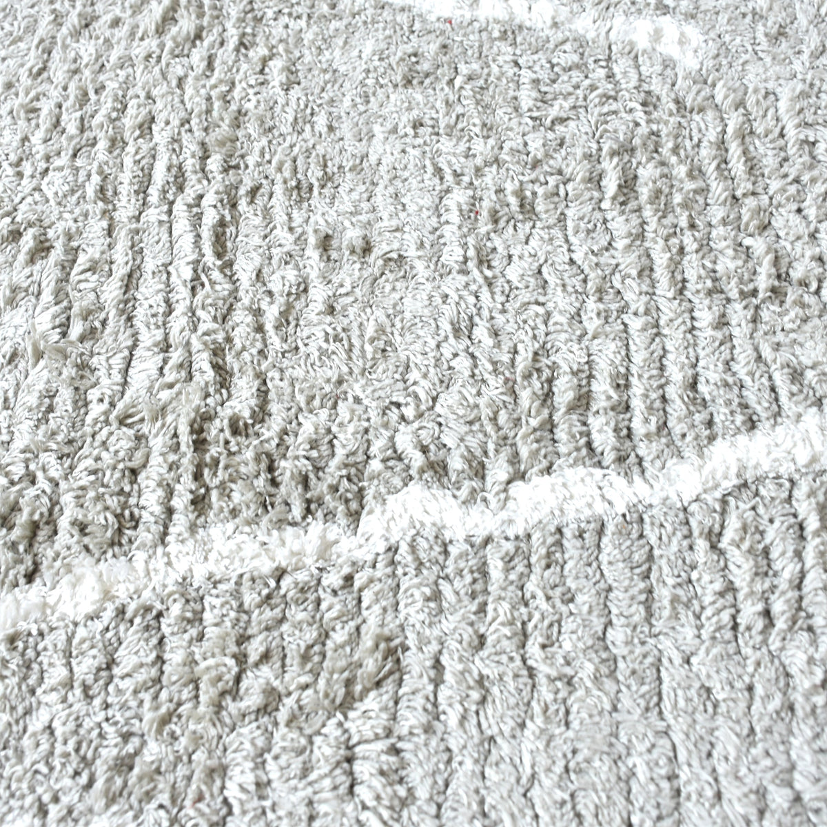 Jugnu tufted cotton and viscose rug with ivory diamond lines on silver grey, in a bedroom