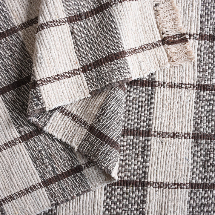 Gamcha handwoven recycled denim flatweave rug with a charcoal-grey and ivory buffalo check, in a living room