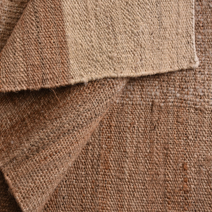 Sunbaked flatweave jute and wool rug in terracotta and blush colour blocks, in a living room