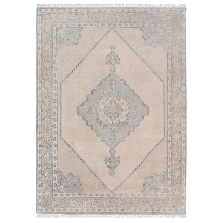 Aab hand-knotted wool rug with a faded blue medallion on an ivory ground, in a living room