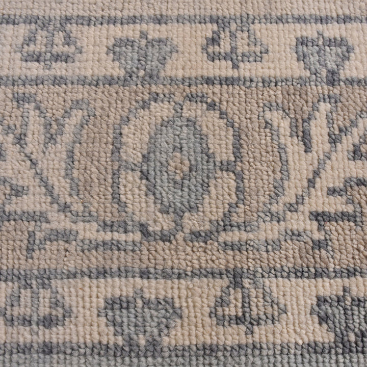 Aab hand-knotted wool rug with a faded blue medallion on an ivory ground, in a living room