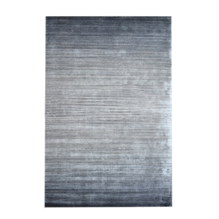 Baadal handwoven wool and viscose rug in streaked grey, charcoal and silver, in a living room