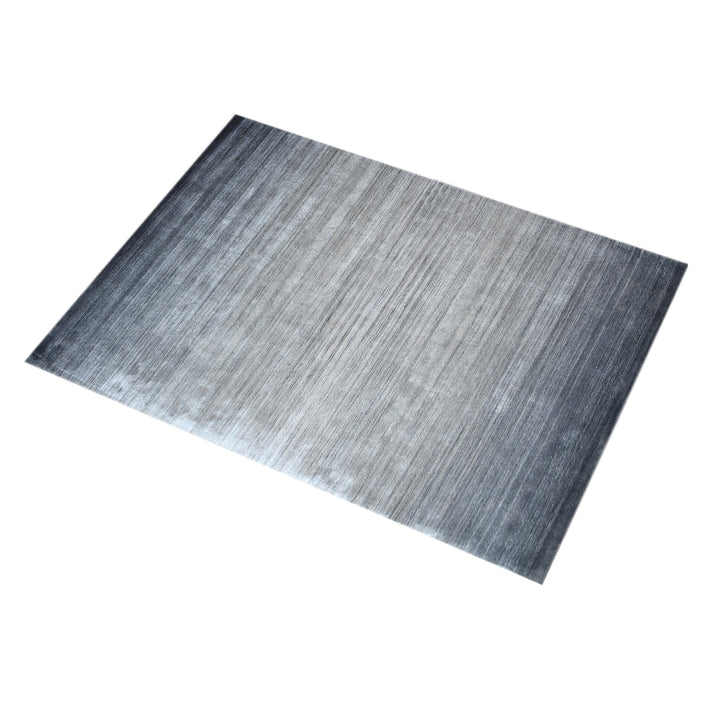 Baadal handwoven wool and viscose rug in streaked grey, charcoal and silver, in a living room