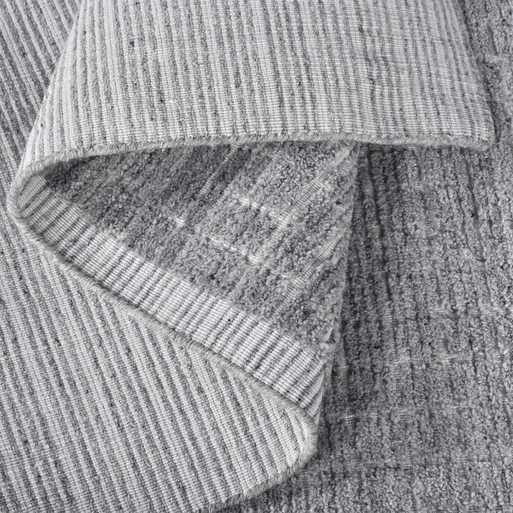 Raakh handwoven flatweave recycled PET rug in plain heather grey with fringe, in a living room