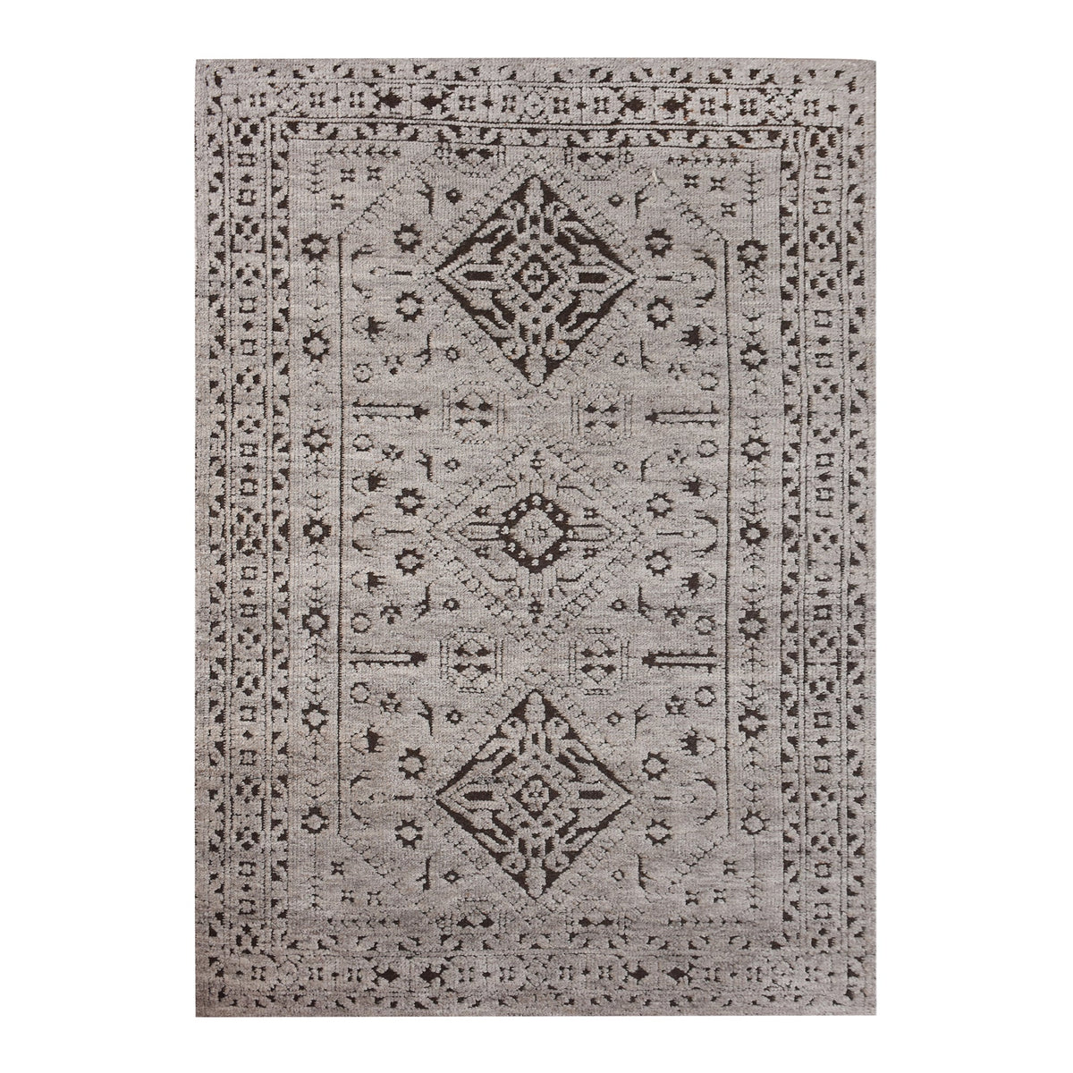 Inkwell hand-knotted ivory wool rug with a faded black tribal medallion, in a living room
