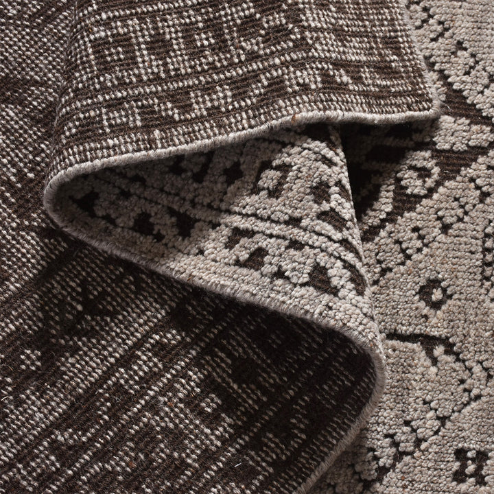 Inkwell hand-knotted ivory wool rug with a faded black tribal medallion, in a living room