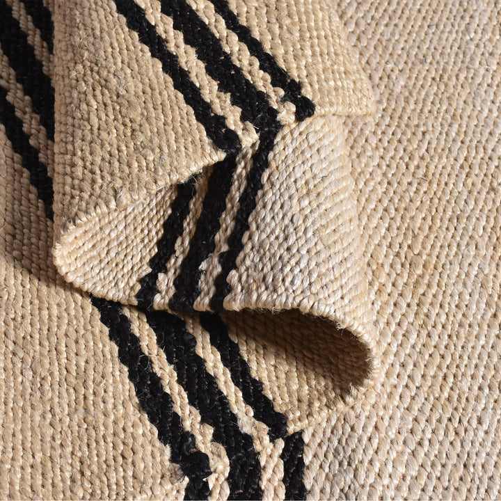 Khaat handwoven natural jute rug with black stripes, in a living room