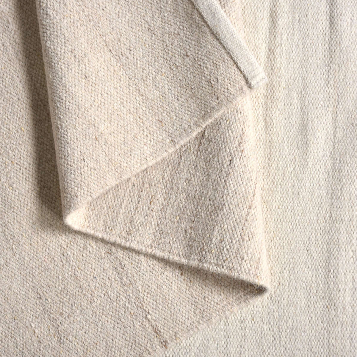 Kamaan handwoven wool flatweave rug with overlapping ivory and beige arcs, in a living room