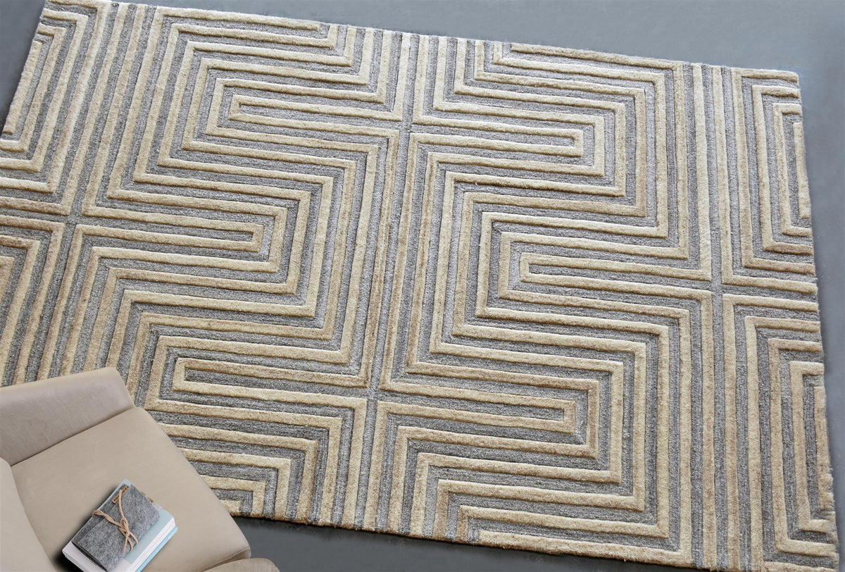 Raasta hand-tufted sand beige wool rug with carved concentric maze lines, in a living room