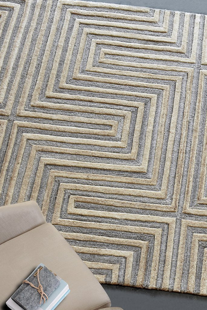 Raasta hand-tufted sand beige wool rug with carved concentric maze lines, in a living room