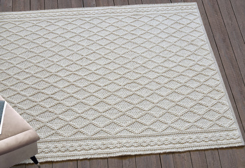 Jaal handwoven ivory wool rug with a raised cabled diamond lattice, in a living room